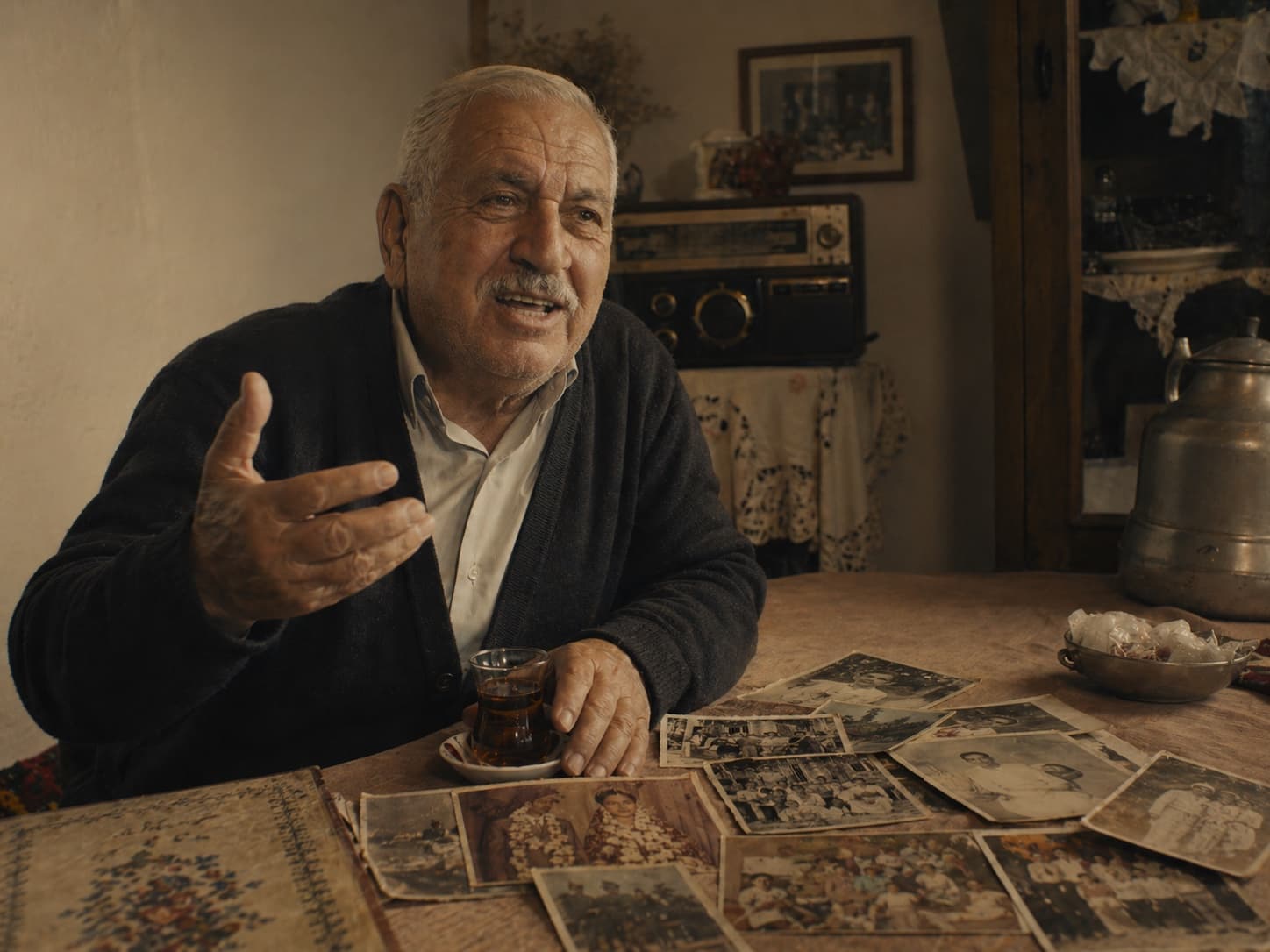 Türkischer Großvater erzählt Familiengeschichten mit alten Fotos auf dem Tisch